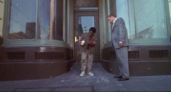 Movie still from “Life Stinks” (1991), directed by Mel Brooks – A man and a woman standing in front of a building; Wide shot, High angle