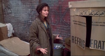Movie still from “Life Stinks” (1991), directed by Mel Brooks – A woman standing in front of a brick wall; Medium shot, Over the shoulder angle