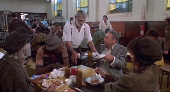 Movie still from “Life Stinks” (1991), directed by Mel Brooks – A group of people sitting at a table with plates of food on it; Wide shot, High angle