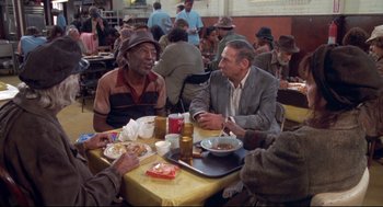 Movie still from “Life Stinks” (1991), directed by Mel Brooks – A group of people sitting at a table with plates of food; Medium shot, High angle