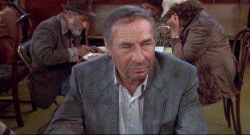 Movie still from “Life Stinks” (1991), directed by Mel Brooks – An older man sitting in front of a group of people; Close Up shot, High angle