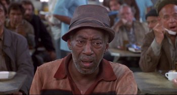 Movie still from “Life Stinks” (1991), directed by Mel Brooks – An older man wearing a brown hat and a brown shirt; Close Up shot, Low angle