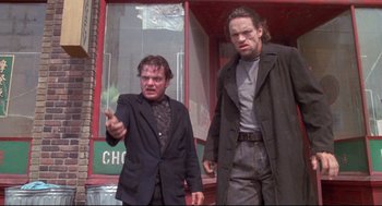 Movie still from “Life Stinks” (1991), directed by Mel Brooks – Two men standing next to each other in front of a building; Medium shot, Low angle