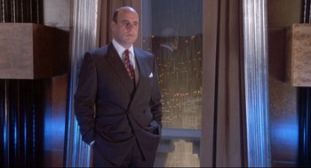 Movie still from “Life Stinks” (1991), directed by Mel Brooks – A man in a suit standing in front of a window; Medium shot, Low angle