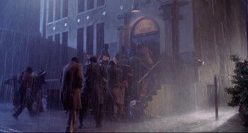 Movie still from “Life Stinks” (1991), directed by Mel Brooks – A group of people standing on the steps of a building in the pouring rain; Wide shot, Low angle