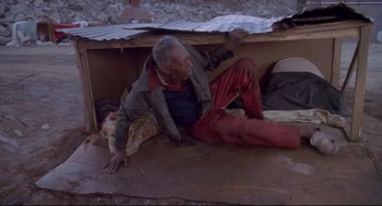 Movie still from “Life Stinks” (1991), directed by Mel Brooks – An older man sitting on the ground in a room; Wide shot, High angle