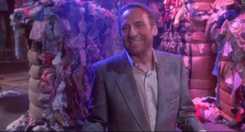 Movie still from “Life Stinks” (1991), directed by Mel Brooks – A man wearing a suit and smiling for the camera; Medium shot, Low angle