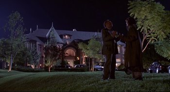 Movie still from “Life Stinks” (1991), directed by Mel Brooks – Two men standing in the grass near a building at night; Wide shot, Low angle