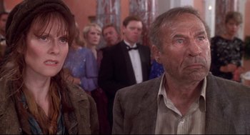 Movie still from “Life Stinks” (1991), directed by Mel Brooks – A man and a woman standing next to each other in front of other people; Close Up shot, Low angle