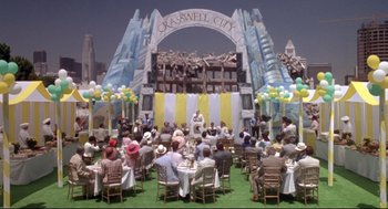Movie still from “Life Stinks” (1991), directed by Mel Brooks – A crowd of people sitting at tables in front of a stage; Extreme Wide shot, High angle