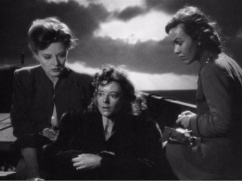 Movie still from “Lifeboat” (1944), directed by Alfred Hitchcock – A group of women sitting next to each other on a dock; Medium shot, High angle
