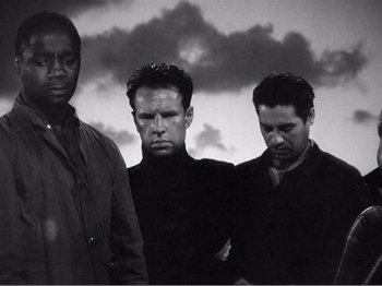 Movie still from “Lifeboat” (1944), directed by Alfred Hitchcock – A group of men standing next to each other in front of a cloudy sky; Medium shot, Low angle