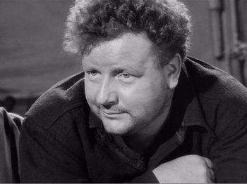 Movie still from “Lifeboat” (1944), directed by Alfred Hitchcock – Black and white photograph of a man leaning on a wall; Close Up shot, High angle