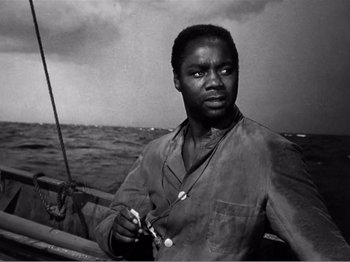 Movie still from “Lifeboat” (1944), directed by Alfred Hitchcock – A black and white photo of a man on a boat in the ocean; Medium shot, Low angle