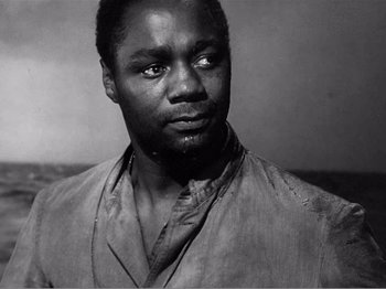 Movie still from “Lifeboat” (1944), directed by Alfred Hitchcock – A black and white photo of a man in a robe; Close Up shot, Over the shoulder angle