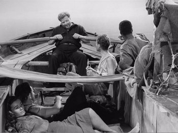 Movie still from “Lifeboat” (1944), directed by Alfred Hitchcock – An older man sitting in a boat on the water; Wide shot, High angle