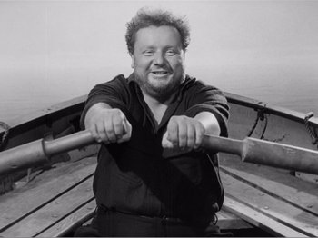Movie still from “Lifeboat” (1944), directed by Alfred Hitchcock – A black and white photo of a man rowing a boat; Close Up shot, High angle