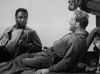 Movie still from “Lifeboat” (1944), directed by Alfred Hitchcock – Two men sitting on the ground talking to each other; Medium shot, Over the shoulder angle