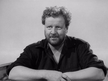 Movie still from “Lifeboat” (1944), directed by Alfred Hitchcock – Black and white photograph of a man with curly hair; Close Up shot, Low angle