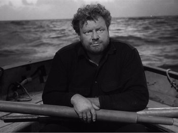 Movie still from “Lifeboat” (1944), directed by Alfred Hitchcock – Black and white photograph of a man sitting in a boat; Close Up shot, High angle