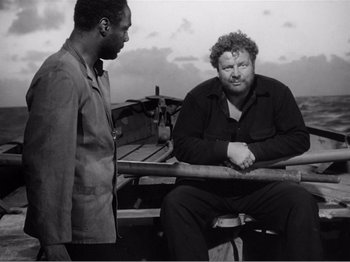 Movie still from “Lifeboat” (1944), directed by Alfred Hitchcock – Two men are sitting on a boat in the water; Medium shot, High angle