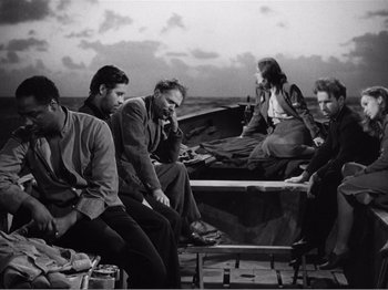 Movie still from “Lifeboat” (1944), directed by Alfred Hitchcock – A black and white photo of a group of people sitting on a boat; Wide shot, High angle