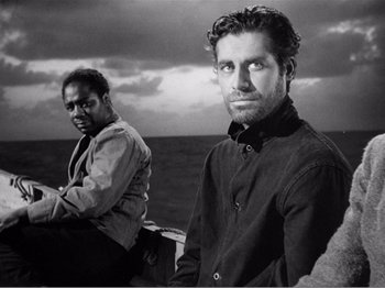 Movie still from “Lifeboat” (1944), directed by Alfred Hitchcock – A black and white photo of two men on a boat in the ocean; Medium shot, High angle