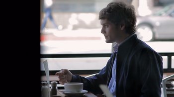 Movie still from “Like Crazy” (2011), directed by Drake Doremus – A man sitting in front of a laptop computer at a table; Medium shot, Over the shoulder angle