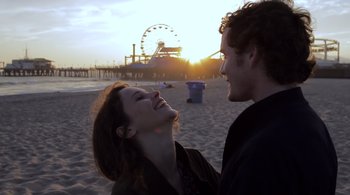 Movie still from “Like Crazy” (2011), directed by Drake Doremus – A man and a woman smile at each other on the beach; Close Up shot, Over the shoulder angle