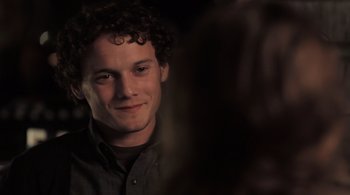 Movie still from “Like Crazy” (2011), directed by Drake Doremus – A man with curly brown hair smiling for the camera; Close Up shot, Over the shoulder angle