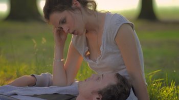 Movie still from “Like Crazy” (2011), directed by Drake Doremus – A young man and a young woman sitting on the grass; Medium shot, Low angle