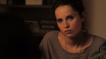 Movie still from “Like Crazy” (2011), directed by Drake Doremus – A beautiful young lady sitting in front of a book shelf; Close Up shot, Over the shoulder angle