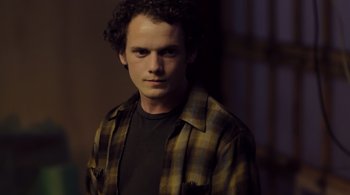 Movie still from “Like Crazy” (2011), directed by Drake Doremus – A man in a brown and black plaid shirt is posing for a picture; Close Up shot, Low angle