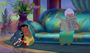 Movie still from “Lilo & Stitch” (2002), directed by Dean DeBlois – A scene of lilo reading a newspaper while lilo sits on the couch; Wide shot, Over the shoulder angle