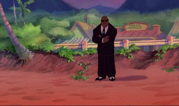 Movie still from “Lilo & Stitch” (2002), directed by Dean DeBlois – An animated man in a black suit standing in front of bushes; Wide shot, Over the shoulder angle