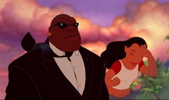 Movie still from “Lilo & Stitch” (2002), directed by Dean DeBlois – A man and a woman are standing in front of clouds; Medium shot, Low angle