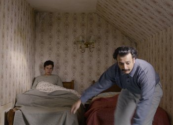 Movie still from “Limbo” (2020), directed by Ben Sharrock – Two men are in a room with a bed; Wide shot, Low angle