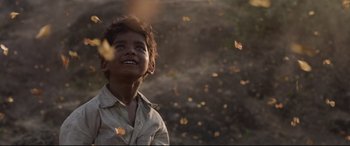 Movie still from “Lion” (2016), directed by Garth Davis – A young boy standing in front of a field of flying leaves; Close Up shot, Low angle