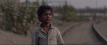 Movie still from “Lion” (2016), directed by Garth Davis – A young boy standing on the side of a train track; Close Up shot, High angle