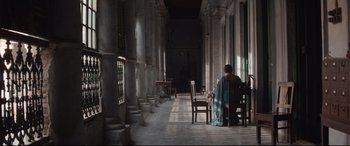 Movie still from “Lion” (2016), directed by Garth Davis – A woman sitting at a table in an empty room; Extreme Wide shot, Low angle