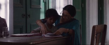 Movie still from “Lion” (2016), directed by Garth Davis – A woman helping a boy with his homework; Medium shot, Low angle