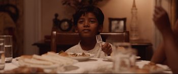 Movie still from “Lion” (2016), directed by Garth Davis – A boy sitting at a table with a plate of food; Close Up shot, High angle