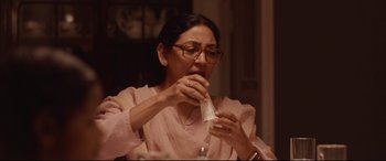 Movie still from “Lion” (2016), directed by Garth Davis – A woman in a pink shirt is eating a sandwich; Close Up shot, Low angle