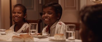 Movie still from “Lion” (2016), directed by Garth Davis – A boy sitting at a dinner table with a piece of cake on a plate; Close Up shot, High angle