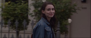 Movie still from “Lion” (2016), directed by Garth Davis – A woman in a jean jacket standing in front of trees; Close Up shot, Over the shoulder angle