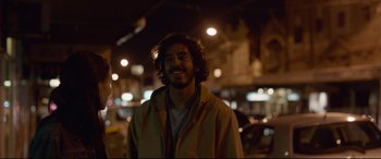 Movie still from “Lion” (2016), directed by Garth Davis – A man with long hair standing in the dark; Close Up shot, Over the shoulder angle