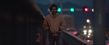 Movie still from “Lion” (2016), directed by Garth Davis – A man standing on the side of a road at night; Medium shot, Low angle