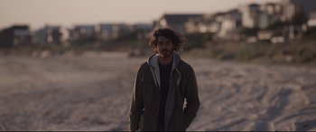 Movie still from “Lion” (2016), directed by Garth Davis – A man with a beard is standing in the sand; Close Up shot, Over the shoulder angle