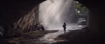 Movie still from “Lion” (2016), directed by Garth Davis – A child running through a puddle near a fire hydrant; Extreme Wide shot, Low angle