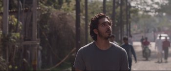 Movie still from “Lion” (2016), directed by Garth Davis – A man with long hair and a beard is looking up; Close Up shot, Over the shoulder angle